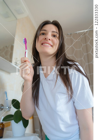 Girl carefully brushes her teeth in the bathroom, taking care of her oral health. She cleans her teeth for a perfect smile. 122833330