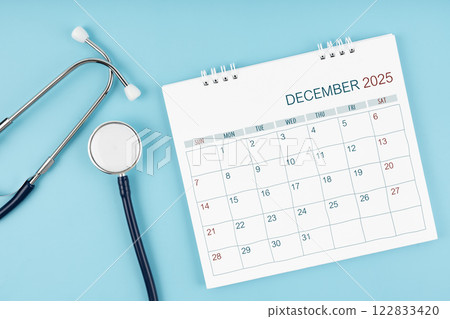 December 2025 desk calendar and stethoscope on blue, Medical appointment concept. 122833420