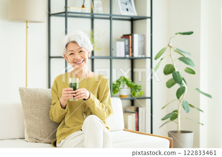 Senior woman drinking green juice in the living room Senior woman drinking green juice in the living room 122833461