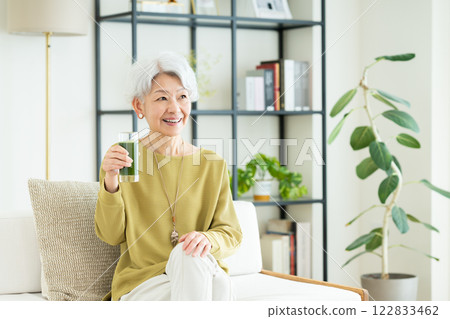 在客廳喝綠汁的老年婦女 在客廳喝綠汁的老年婦女 122833462