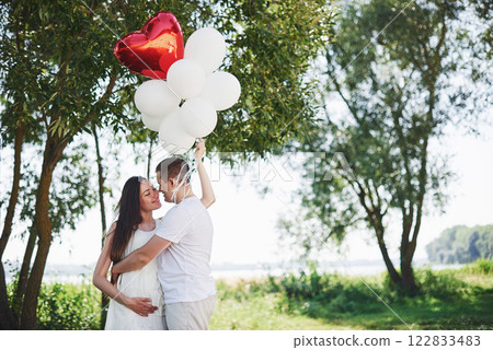 Happy and young pregnant couple hugging in nature. Romantic moments Happy and young pregnant couple hugging in nature. Romantic moments 122833483