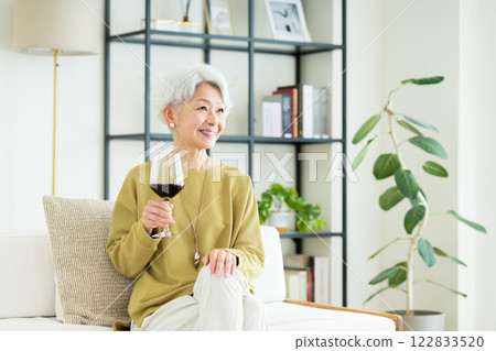 Senior woman drinking wine in the living room Senior woman drinking wine in the living room 122833520