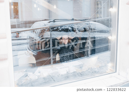 Young man drinking coffee in cafe looking out the window Young man drinking coffee in cafe looking out the window 122833622