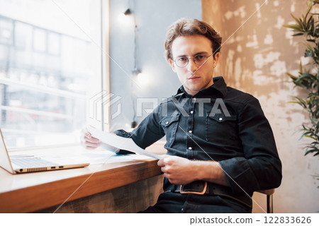 Relaxed young professional surfing the Internet on his laptop in a cafe Relaxed young professional surfing the Internet on his laptop in a cafe 122833626