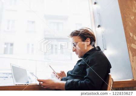 Relaxed young professional surfing the Internet on his laptop in a cafe 122833627