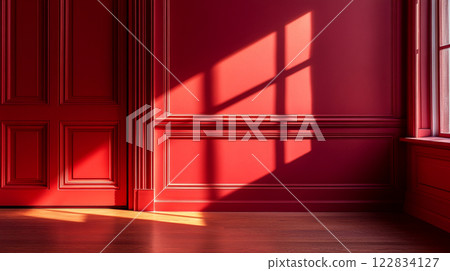 Red room with a window and a shadow on the wall. The room is empty and the red walls and wooden floors create a warm and inviting atmosphere 122834127