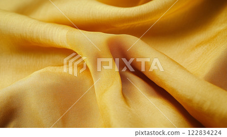 Yellow fabric with a pattern on it. The fabric is folded and has a slightly wrinkled appearance 122834224