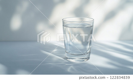 Glass of water is sitting on a table. The glass is half full and the water is clear 122834839