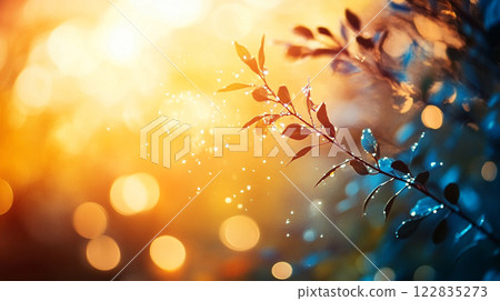 Leafy branch with a bright orange and blue background. The leaves are covered in a light mist 122835273