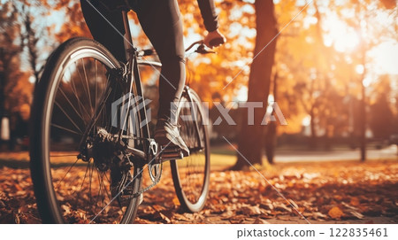 Cyclist riding through a park covered with autumn leaves 122835461