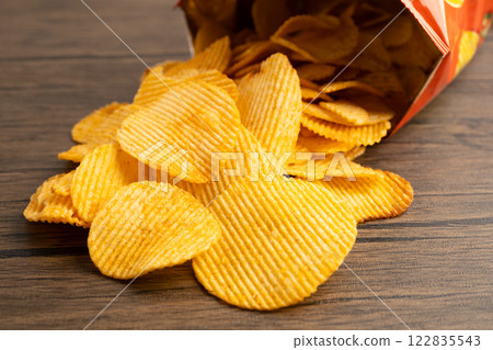 Potato chips, delicious BBQ seasoning spicy for crips, thin slice deep fried snack fast food in open bag. 122835543