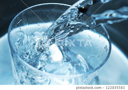 Water being poured vigorously into a glass 122835581