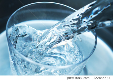 Water being poured vigorously into a glass 122835585