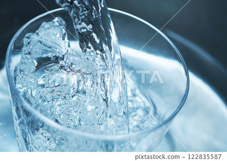 Water being poured vigorously into a glass 122835587