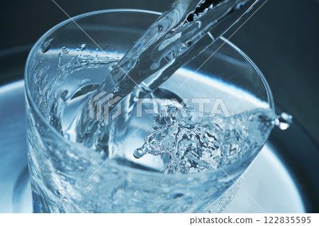 Water being poured vigorously into a glass 122835595