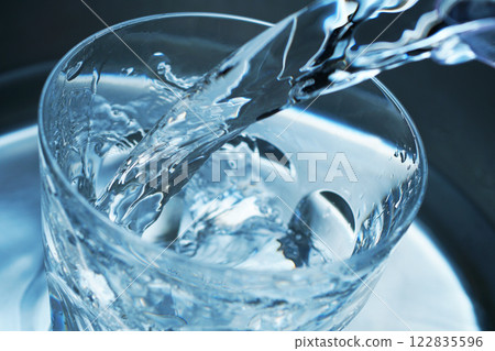Water being poured vigorously into a glass 122835596