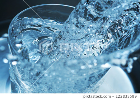 Water being poured vigorously into a glass 122835599