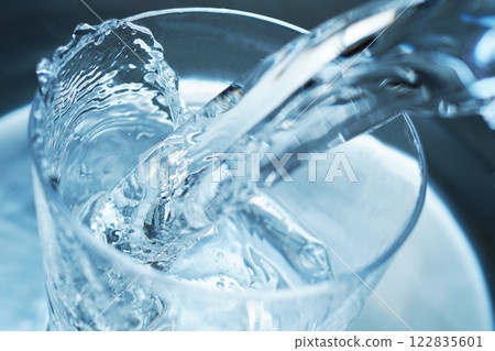 Water being poured vigorously into a glass 122835601