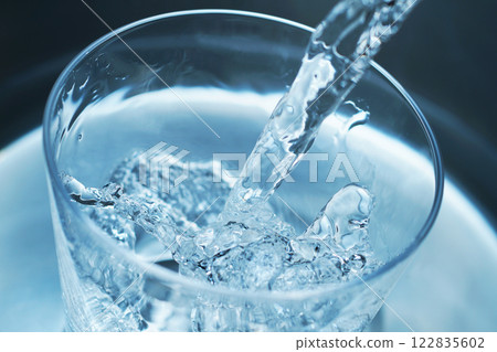 Water being poured vigorously into a glass 122835602