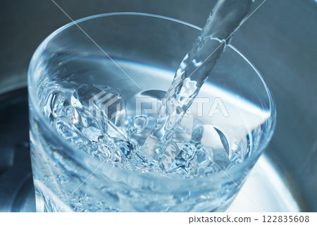 Water being poured vigorously into a glass 122835608