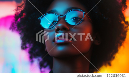 Woman with curly hair and glasses is looking at the camera. The image has a vibrant and colorful feel to it, with the woman's hair and glasses contrasting against the bright background Woman with curly hair and glasses is looking at the camera. The image has a vibrant and colorful feel to it, with the woman's hair and glasses contrasting against the bright background 122836081
