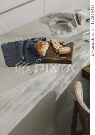 Sliced bread in linen bag on wooden board, fresh herbs and stainless still kitchen knife. Kitchen aesthetic concept 122836452