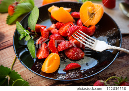 fresh fruit salad of ripe strawberries and apricots, on a light wooden table fresh fruit salad of ripe strawberries and apricots, on a light wooden table 122836538