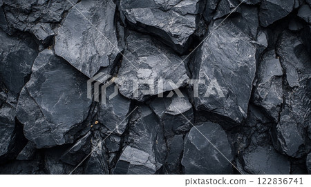 Close up of a pile of rocks. The rocks are black and grey in color. Concept of ruggedness and strength, as the rocks are piled high and seem to be unyielding Close up of a pile of rocks. The rocks are black and grey in color. Concept of ruggedness and strength, as the rocks are piled high and seem to be unyielding 122836741