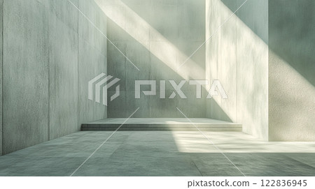 Large, empty room with a concrete wall and a concrete floor. The room is illuminated by sunlight coming in through a window 122836945