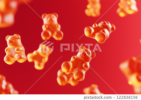 Red gummy bears floating in air on a vibrant red background. Gummy bear candies suspended in mid-air over bright backdrop. Sweets and happy childhood concept. 122838156