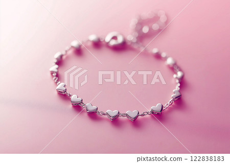 Elegant silver heart bracelet on a soft pink background, romantic design. Delicate heart-shaped bracelet in silver tones, elegance and love symbol on pink. Fashion jewelry, Saint Valentine's Day gift 122838183