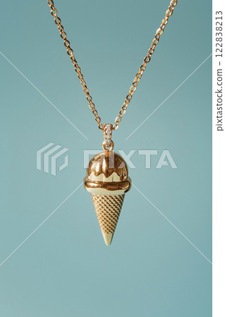 Elegant golden ice cream cone necklace on a light blue background. White gold ice cream cone jewelry pendant. Sweets and fast fashion concept. Rip diet, creative jewelry. Summer vibes, holidays. 122838213