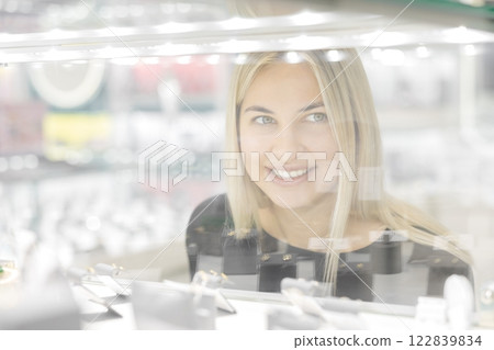 Woman looking on jewelry behind glass display in a store 122839834