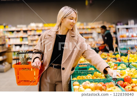 Woman holding apple and shopping basket buying groceries at supermarket 122839840