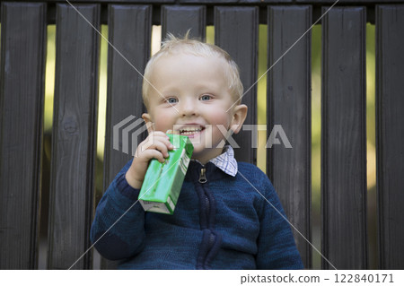 The child is drinking juice from the tube for a walk 122840171