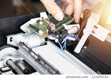 Top view of technician inspecting and repairing printer and motherboard. Top view of technician inspecting and repairing printer and motherboard. 122840183