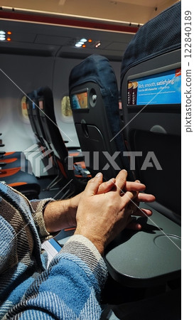 Empty airplane cabin. Male hands on the table in the airplane cabin during landing 122840189