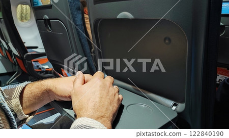 Empty airplane cabin. Male hands on the table in the airplane cabin during landing 122840190