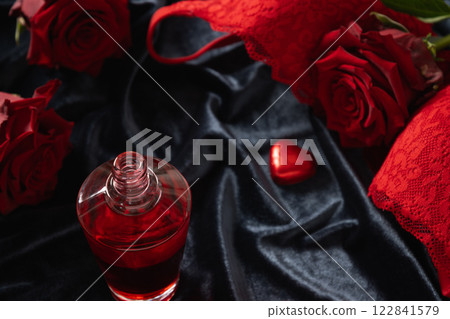 Romantic dating. Valentine's day, lace women's red underwear, lingerie, massage oil and red roses on dark blue. Adult body massage. Copy space. Close up. Romantic dating. Valentine's day, lace women's red underwear, lingerie, massage oil and red roses on dark blue. Adult body massage. Copy space. Close up. 122841579