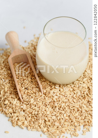 Vegan non dairy alternative oat milk in glass. Oat cereal in wooden spoo on stone table. concept of vegetarian diet eating, dieting, sport and fitness menu Vegan non dairy alternative oat milk in glass. Oat cereal in wooden spoo on stone table. concept of vegetarian diet eating, dieting, sport and fitness menu 122842050