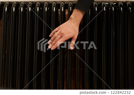 A woman checks the radiator in a cold apartment. Modern radiator for heating in an apartment with power regulators. There is a problem with central heating in the house. High quality photo A woman checks the radiator in a cold apartment. Modern radiator for heating in an apartment with power regulators. There is a problem with central heating in the house. High quality photo 122842232