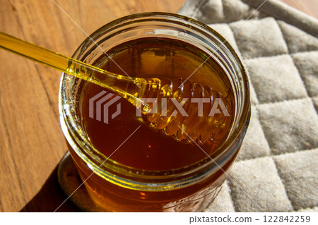Honey jar with honeycomb and yellow spoon stay on the wood table. Honey jar with honeycomb and yellow spoon stay on the wood table. 122842259