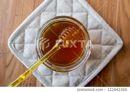 Honey jar with honeycomb and yellow spoon stay on the wood table. 122842260