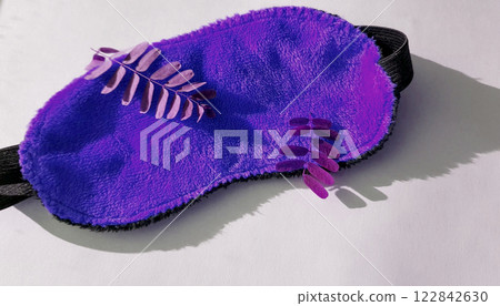 Camera movement over a soft orange eye mask lying in the morning on a white background with twigs of plants, top view. Healthy sleep concept Camera movement over a soft orange eye mask lying in the morning on a white background with twigs of plants, top view. Healthy sleep concept 122842630