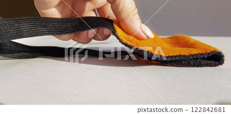 A woman's hand strokes a soft orange sleep mask lying on a white background with bright sunlight in the morning. Healthy sleep concept A woman's hand strokes a soft orange sleep mask lying on a white background with bright sunlight in the morning. Healthy sleep concept 122842681