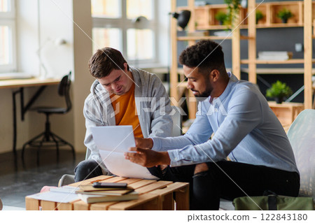 Young man with Down syndrome studyng with special educator teacher in special education classroom. 122843180