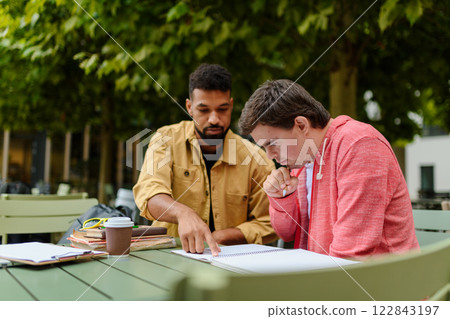 Young man with Down syndrome studyng with special educator teacher. 122843197