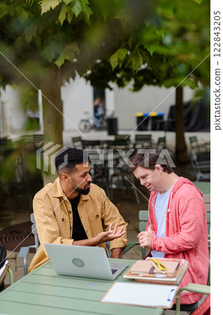 Young man with Down syndrome studyng with special educator teacher. 122843205