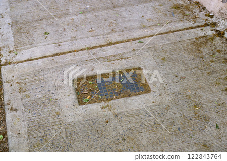 A dirty concrete sidewalk that has a door mat placed on it A dirty concrete sidewalk that has a door mat placed on it 122843764