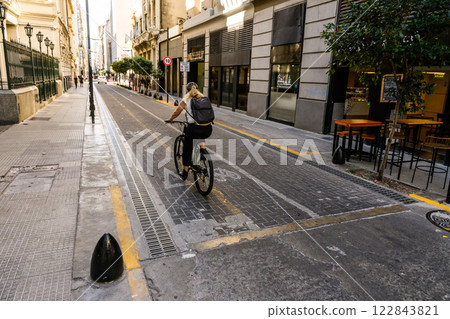 A person is riding a bicycle down a bustling city street today 122843821